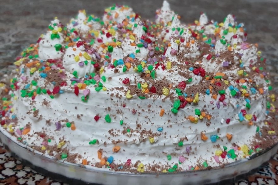 عکس کیک ساده خانگی با روکش خامه و سنگهای شکلاتی و پودر نسکافه