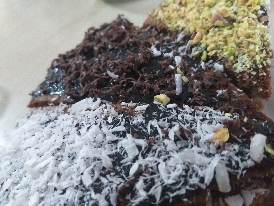 عکس کیک خیس با روکش سس شکلات و تزیین پسته' نارگیل و کاکائو 